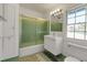 Retro-style bathroom with green and white tile, modern vanity, and shower with sliding glass doors at 259 S Polk Dr, Sarasota, FL 34236