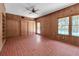 Spacious living room with wood paneled walls, brick floors, a ceiling fan, and sliding door access to the pool at 259 S Polk Dr, Sarasota, FL 34236