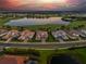 Panoramic aerial view of a neighborhood, golf course, and lake with a beautiful sunset sky at 3936 Santa Caterina Blvd, Bradenton, FL 34211