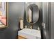 Stylish powder room featuring dark walls, a modern mirror, and minimalist decor at 3936 Santa Caterina Blvd, Bradenton, FL 34211