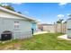 Private backyard features a blue door, a grill, seating, well-maintained lawn, and privacy fence at 453 Sandlewood Dr, Venice, FL 34293