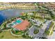 Stunning aerial view of the community clubhouse with a pool, tennis courts, and scenic lake at 4916 Tivoli Run, Bradenton, FL 34211
