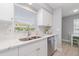 Bright kitchen featuring white cabinets, a marble countertop, stainless steel appliances, and a view through the window at 522 Pine Ave # 8B, Anna Maria, FL 34216