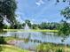 Picturesque view of a community pond with a central fountain surrounded by lush greenery and a vibrant blue sky at 5620 Whitehead St, Bradenton, FL 34203
