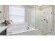 Beautiful bathroom with marble tile, a soaking tub, and a frameless glass shower enclosure at 5927 Maidenstone Way, Palmetto, FL 34221