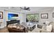 Comfortable living room featuring a large tv, wood flooring, and a screened-in lanai with outdoor seating at 5927 Maidenstone Way, Palmetto, FL 34221