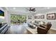 Bright living room with hardwood floors, a ceiling fan, gray sofa, and a screened-in lanai at 5927 Maidenstone Way, Palmetto, FL 34221
