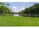A grassy backyard featuring a pond with a fence and lush greenery at 6114 68Th E Dr, Palmetto, FL 34221