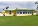 Back view of a yellow home with a light green roof and well-manicured lawn at 6114 68Th E Dr, Palmetto, FL 34221