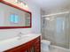Bright bathroom features a glass enclosed shower, tile surround, single sink vanity with cherry wood cabinet at 6341 Cocoa Ln, Apollo Beach, FL 33572