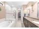 Bright bathroom featuring double vanities, soaking tub, a glass enclosed shower, and a spacious walk-in closet at 6854 Chester Trl, Lakewood Ranch, FL 34202