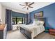 Cozy bedroom with blue walls, a ceiling fan, and a comfortable queen-sized bed at 6854 Chester Trl, Lakewood Ranch, FL 34202