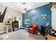 The bonus room has blue accent walls, a cozy red chair, modern lighting, and custom decor at 6854 Chester Trl, Lakewood Ranch, FL 34202