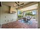 Lanai featuring brick flooring, a ceiling fan, and an outdoor kitchen space, with a view of the pond at 6854 Chester Trl, Lakewood Ranch, FL 34202
