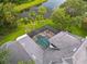 Aerial view of beautiful home featuring a screened-in pool surrounded by tropical landscaping and serene water feature at 6959 Westchester Cir, Bradenton, FL 34202
