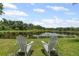 Inviting Adirondack chairs offering a peaceful view of the tranquil pond and surrounding lush greenery at 6959 Westchester Cir, Bradenton, FL 34202