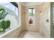 Spa-like bathroom featuring bright, natural stone, dual shower heads, and natural light from two windows at 6959 Westchester Cir, Bradenton, FL 34202