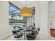 Modern dining room with a round glass table and seating overlooking the screened-in pool and lake at 6959 Westchester Cir, Bradenton, FL 34202
