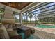 Outdoor living space with a screened-in pool, comfortable seating, stone fireplace, and views of the lush greenery at 6959 Westchester Cir, Bradenton, FL 34202