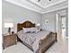 Spacious main bedroom featuring a tray ceiling, decorative headboard and ensuite access at 7037 Brier Creek Ct, Lakewood Ranch, FL 34202