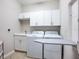 Clean laundry room with modern washer and dryer, ample cabinet space, utility sink and ironing board at 7387 Divot Loop # 15-D, Lakewood Ranch, FL 34202