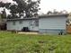 View of the home's backyard, featuring lawn and a light blue exterior at 7555 15Th N St, St Petersburg, FL 33702