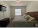 Bright bedroom featuring a bed with tropical-patterned bedding and natural light from the window at 8995 Milestone Dr, Sarasota, FL 34238