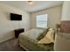 Bright bedroom featuring a bed with tropical-patterned bedding and natural light from the window at 8995 Milestone Dr, Sarasota, FL 34238