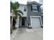 Two-story townhome featuring a one-car garage, neutral paint, and a well-maintained front yard with a palm tree at 8995 Milestone Dr, Sarasota, FL 34238