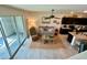 Open-concept living room with sliding glass doors, neutral tones, ceiling fan, and adjacent kitchen area at 8995 Milestone Dr, Sarasota, FL 34238