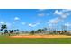 Community baseball field with red dirt, bench seating, fencing, and lush green landscaping at 9292 Tequila Sunrise Dr, Sarasota, FL 34241