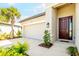 Close-up of the garage, walkway, and entrance, highlighting the beautiful brown front door and manicured landscaping at 9292 Tequila Sunrise Dr, Sarasota, FL 34241