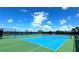 Tennis courts with a vibrant blue court and green surrounding. Palm trees and lake in background at 9292 Tequila Sunrise Dr, Sarasota, FL 34241