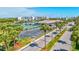 Aerial view showcasing a tennis court, parking, and lush landscaping near the lake at 10037 62Nd N Ter # 23, St Petersburg, FL 33708
