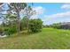 Expansive backyard featuring mature trees, pond access, and partial view of screened lanai at 1071 Owl Dr, Englewood, FL 34223
