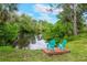 Peaceful backyard pond view with two Adirondack chairs on a small dock at 1071 Owl Dr, Englewood, FL 34223