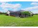 Lush backyard showcasing a screened lanai, landscaped greenery, and a spacious lawn at 1071 Owl Dr, Englewood, FL 34223