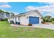Exterior shot of the home featuring a bright blue garage door and well-kept landscaping at 1071 Owl Dr, Englewood, FL 34223
