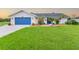 Charming single-story home with a well-manicured lawn, blue garage door, and inviting landscaping at 1071 Owl Dr, Englewood, FL 34223