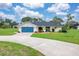 Well-maintained single-story home with a bright blue garage door and manicured landscaping at 1071 Owl Dr, Englewood, FL 34223