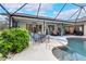 Enclosed pool area offering a covered seating, dining spaces, and exterior landscaping at 1071 Owl Dr, Englewood, FL 34223