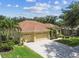 Exterior of a well-maintained home with a three-car garage, mature trees, and a green lawn at 11009 Wildcat Dr, Riverview, FL 33579