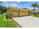 View of a well-maintained home with a three-car garage, mature tree, and green lawn at 11009 Wildcat Dr, Riverview, FL 33579