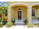 Charming covered front entryway with lush landscaping and a decorative glass door at 11009 Wildcat Dr, Riverview, FL 33579