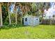 A cozy, light-blue storage shed nestled on a lush green lawn beneath the shade of tall palm trees at 116 Myakka Dr, Venice, FL 34293