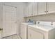 Functional laundry room features white cabinetry and modern washer and dryer at 12113 Whistling Way, Lakewood Ranch, FL 34202