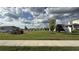 View of community green space, showcasing a large lawn with trees and neighborhood homes under a cloudy sky at 14312 Crimson Ave, Bradenton, FL 34211