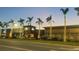 Street view of a shopping center at dusk, featuring various stores and palm trees lit with festive lights at 14312 Crimson Ave, Bradenton, FL 34211