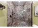 Walk-in shower features gorgeous stone tile, glass surround, bronze fixtures, and a built-in corner bench at 1610 Bayshore Dr, Terra Ceia, FL 34250