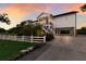 Charming two-story waterfront home featuring a white picket fence, lush landscaping, and elevated construction at 1610 Bayshore Dr, Terra Ceia, FL 34250